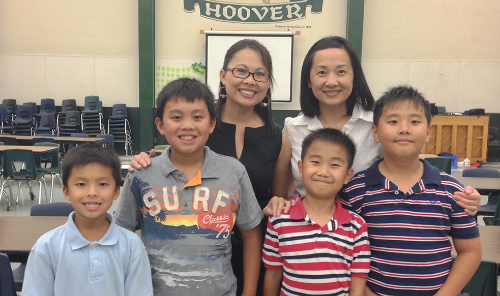 Dr. Lee posing with another woman and 4 young boys