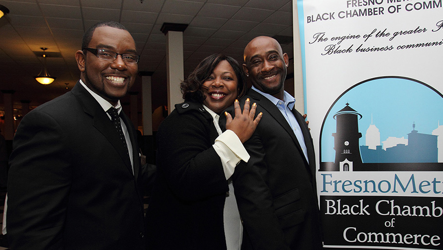Tate Hill posing and smiling with a couple other guests at the Fresno Metro Black Chamber of Commerce meeting