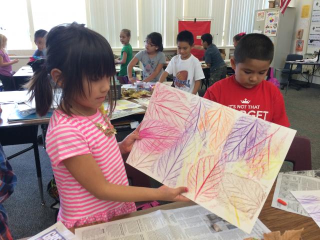Student showing their leaf art project